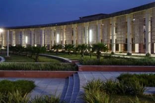 Photograph of a landscaped courtyard between long colonnaded wings at dusk.