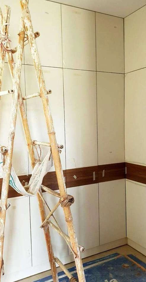 Site photograph of the walk-in closet with panelled doors installed and a bamboo ladder against the wall.